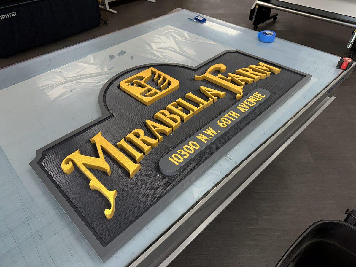 Mirabella Farm carved HDU sign with raised yellow letters on textured dark grey background — fabricated by CG Signs
