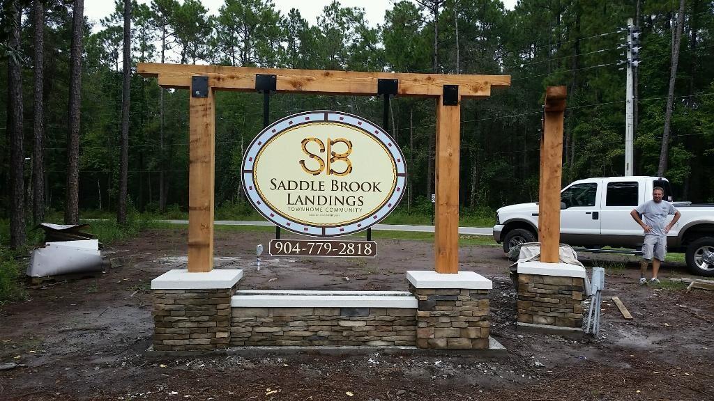 Stacked stone base with cedar post structure and aluminum sign faces — CG Signs