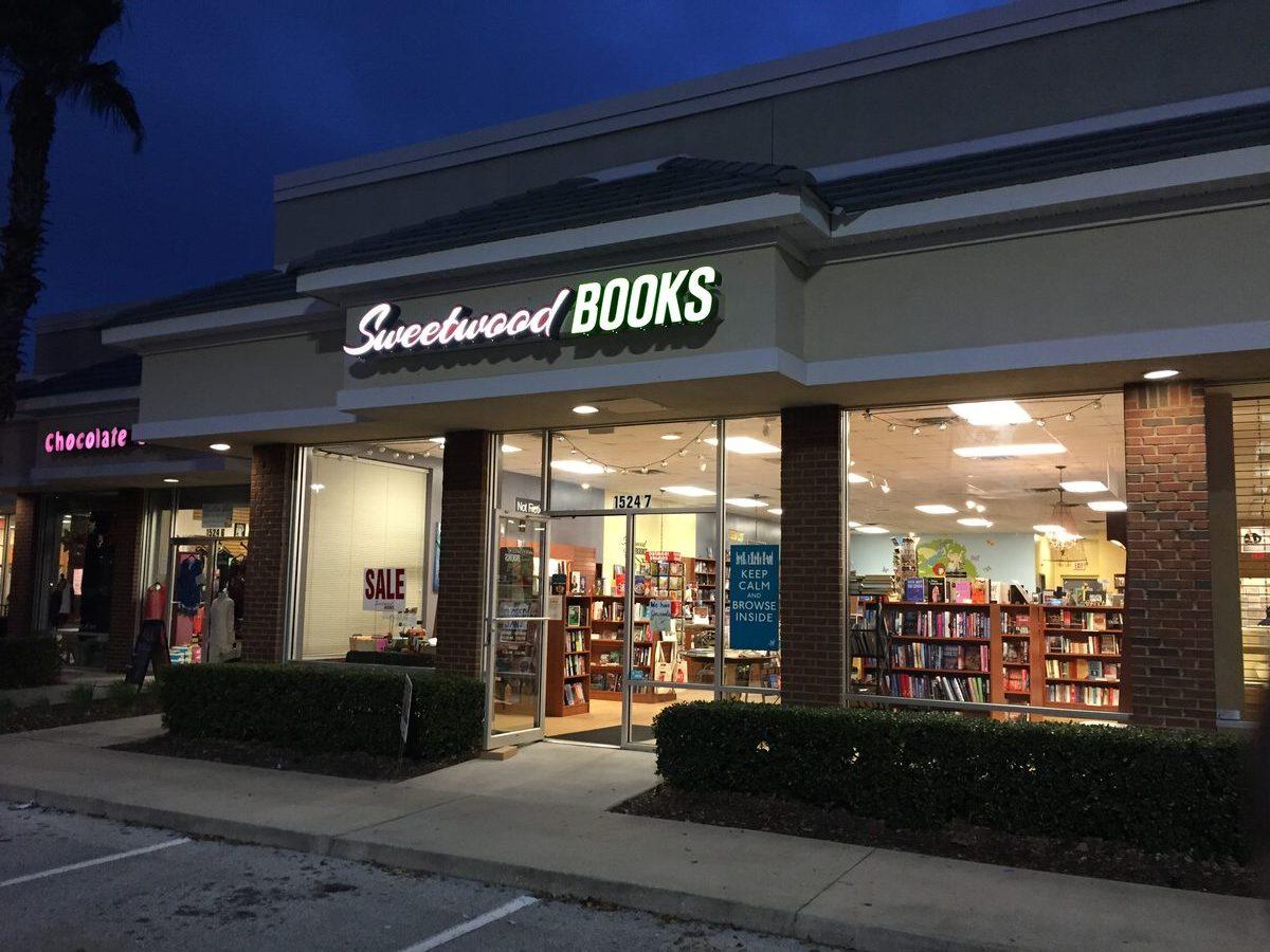 Sweetwood Books storefront with illuminated channel letters at night — script Sweetwood paired with block BOOKS, fabricated and installed by CG Signs in Fleming Island FL