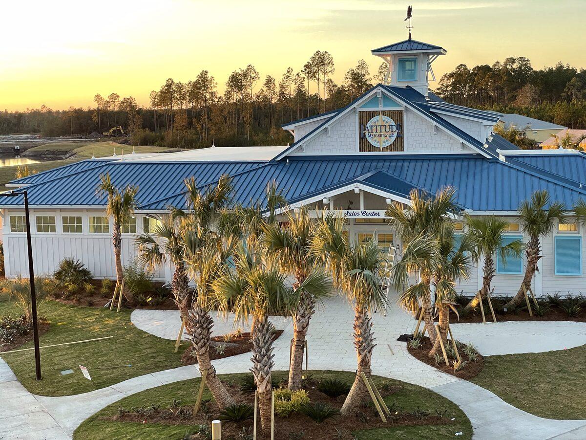 Sales Center building at sunset with layered PVC Latitude Margaritaville identity sign on the roof gable — Watersound, FL — by CG Signs