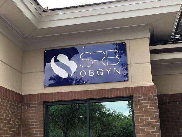Acrylic panel sign with second surface purple vinyl background color and first surface dimensional acrylic letters with brushed aluminum finish for SRB OBGYN in Jacksonville — Custom Graphics & Sign Designs