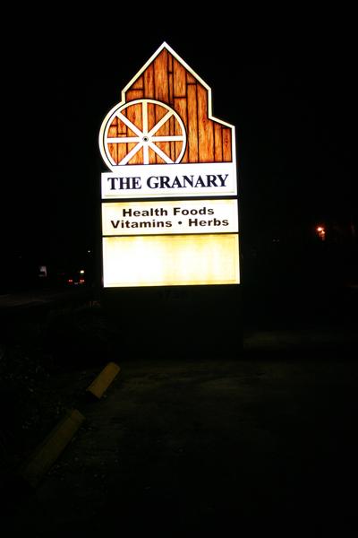 Illuminated barn-shaped monument sign with wagon wheel detail for The Granary Health Foods — Custom Graphics & Sign Designs, Jacksonville FL