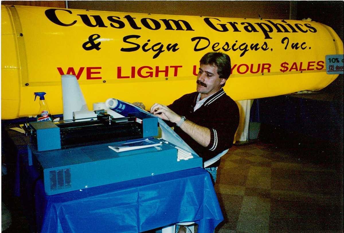 Marvin Thole operating a Gerber IV B vinyl plotter at the Jacksonville Home and Patio Show in the early 1990s — Custom Graphics & Sign Designs Inc. founder heritage photo